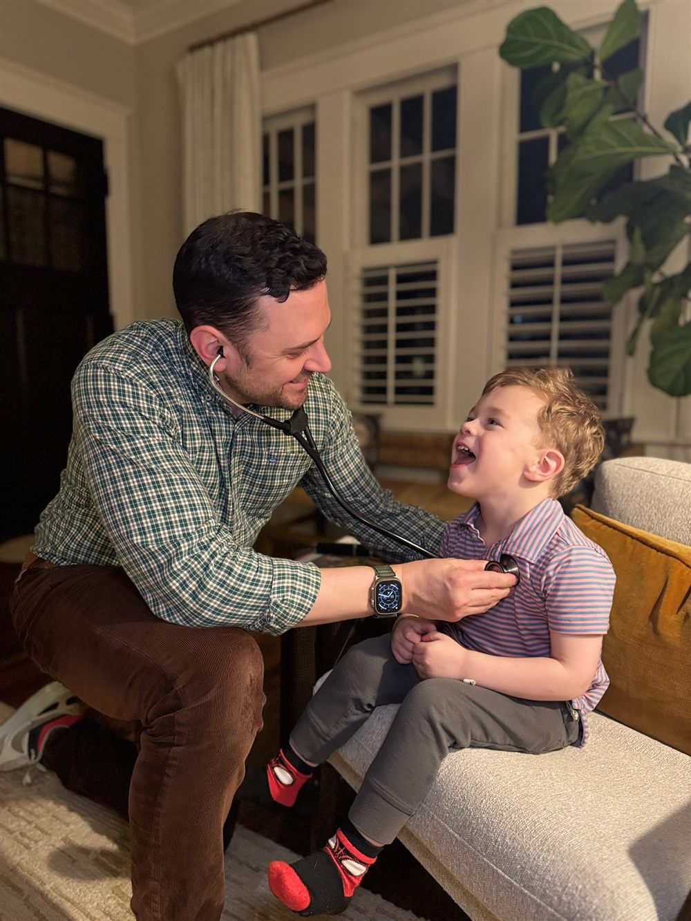 Dr. Trey examining a smiling child at home with a stethoscope